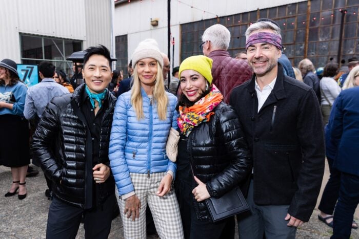 Four people in puffy jackets and beanies smile for the camera